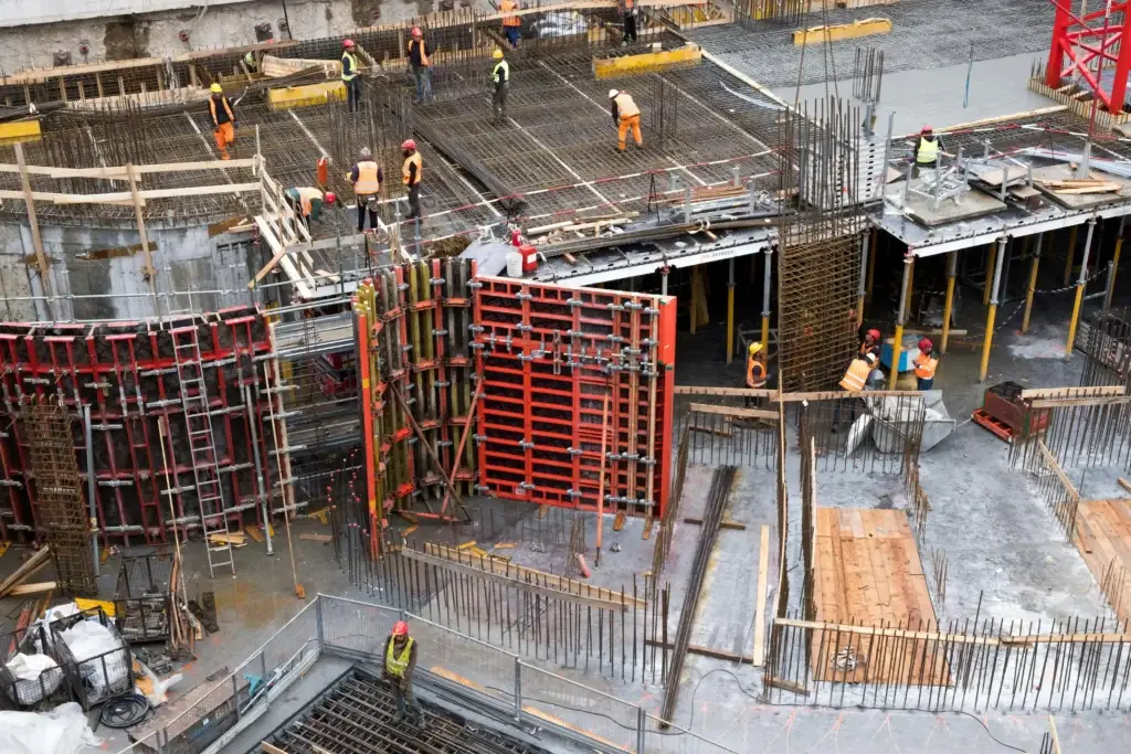 Aerial view of an active construction site with workers, rebar, and concrete formwork, representing Uzoma Sudarma, a Sugar Land, Texas personal-injury and estate law firm.