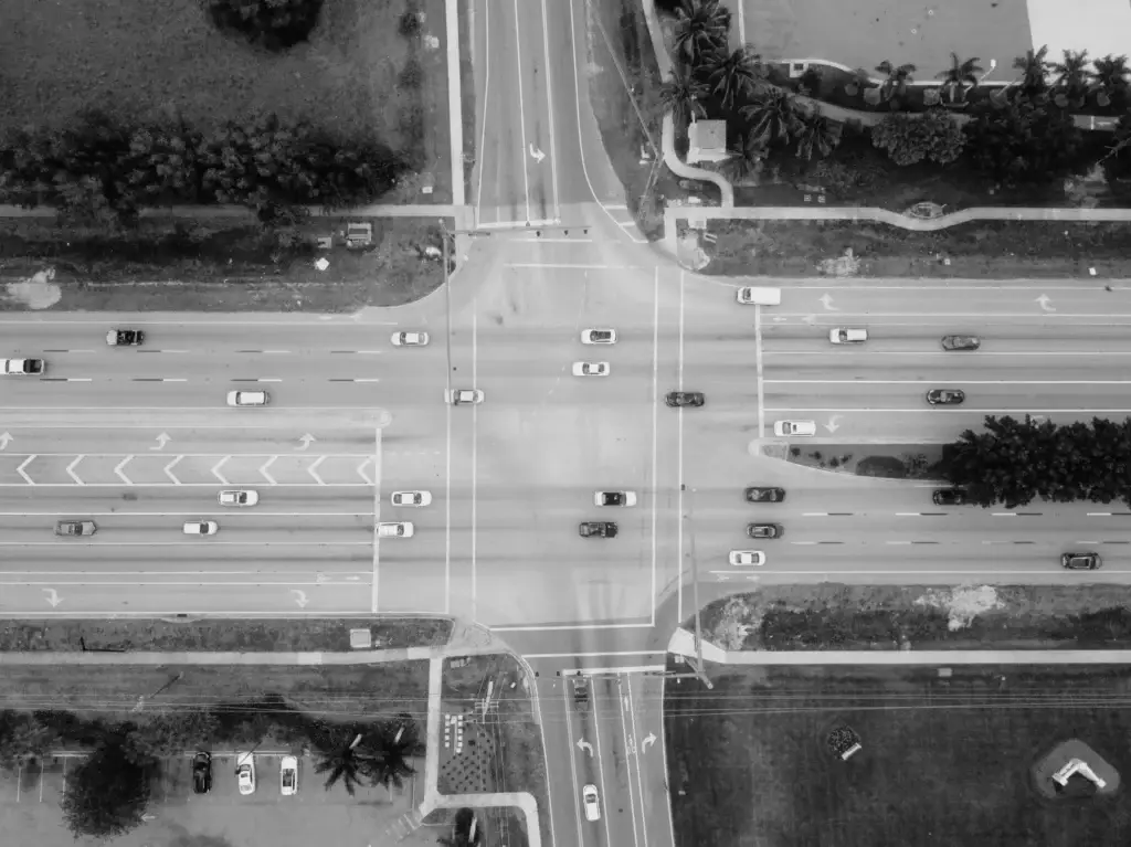 Aerial black-and-white view of a busy multi-lane road intersection with traffic, representing car accident and personal injury cases handled by Uzoma Sudarma in Sugar Land, Texas.